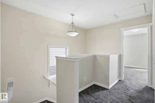 Upper-level landing featuring textured carpeting, a window with horizontal blinds, and a suspended ceiling fixture - 445 Watt Boulevard, Edmonton, AB 