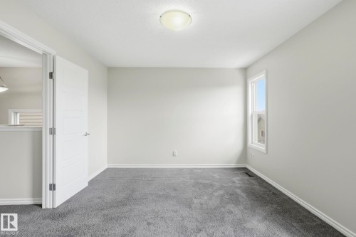Spacious room featuring neutral wall tones, gray carpeting, a single window, and a modern light fixture - 445 Watt Boulevard, Edmonton, AB 
