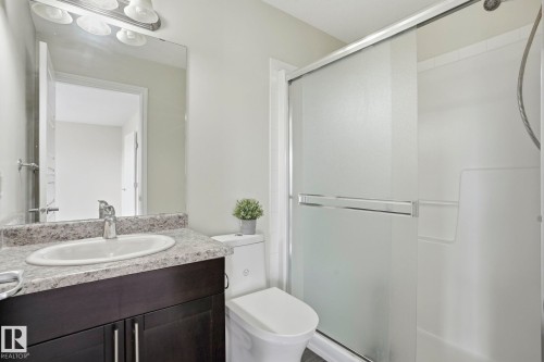 Full bathroom featuring a dark wood-finish vanity with a speckled countertop, an oval undermount sink, and a chrome faucet - 445 Watt Boulevard, Edmonton, AB 
