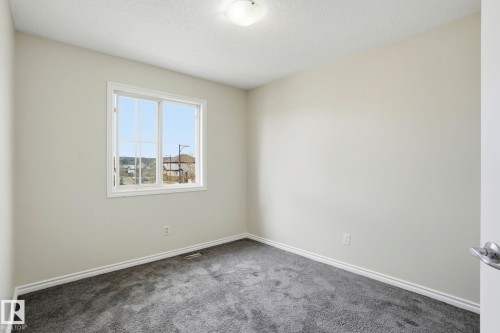 Bright room featuring a window with white trim, neutral wall paint, gray carpet, white baseboards, and a ceiling-mounted light fixture - 445 Watt Boulevard, Edmonton, AB 