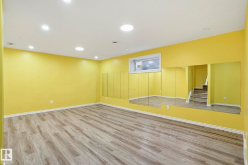 Spacious room featuring wood-finish flooring, recessed lighting, a built-in mirror wall, and a window providing natural illumination - 445 Watt Boulevard, Edmonton, AB 