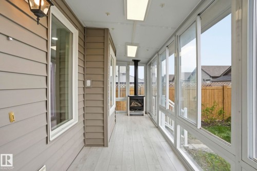 Sunroom featuring light wood-finish flooring, full-length windows, a freestanding stove, and ceiling-mounted lighting - 445 Watt Boulevard, Edmonton, AB 
