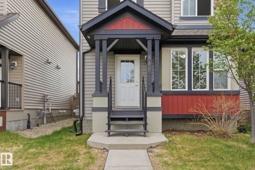 Inviting front entrance featuring a covered porch with dark trim and red accents - 445 Watt Boulevard, Edmonton, AB 