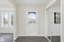 Entryway with dark tile flooring, white paneled door featuring multiple glass panes, and a mirrored closet door - 445 Watt Boulevard, Edmonton, AB 