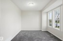 Bright interior space featuring a trio of large windows with white trim, gray wall-to-wall carpeting, light neutral wall paint, and a flush-mount ceiling light fixture - 445 Watt Boulevard, Edmonton, AB 