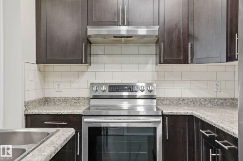 Modern kitchen featuring dark wood-finish cabinetry, stainless steel appliances, and subway tile backsplash - 445 Watt Boulevard, Edmonton, AB 