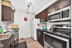 Kitchen featuring dark wood cabinetry, a stainless steel over-the-range microwave, and a stainless steel electric range - 