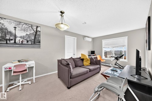 Spacious room featuring neutral carpeting, a large window with horizontal blinds, and a built-in air conditioning unit - 417 1510 Watt Drive, Edmonton, AB 
