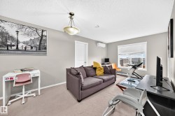 Spacious room featuring neutral carpeting, a large window with horizontal blinds, and a built-in air conditioning unit - 