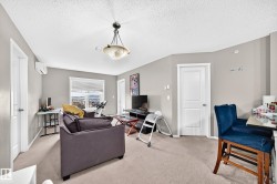 Carpeted common area featuring light gray walls, a window with horizontal blinds, and a built-in air conditioning unit - 