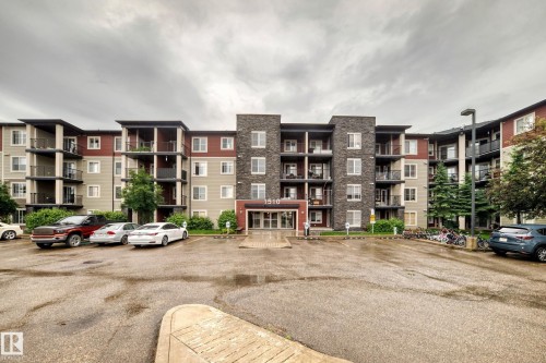 Multi-story residential building featuring a stone and stucco facade, private balconies, and a designated parking area - 417 1510 Watt Drive, Edmonton, AB 