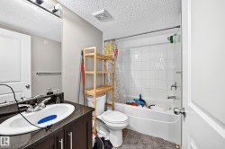Bathroom featuring a vanity with dark cabinetry and countertop, a white drop-in sink, and a chrome faucet - 