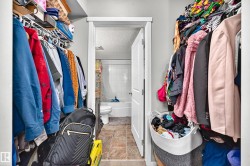 Walk-in closet featuring wire shelving, hanging rods, and an entryway to a full bathroom with a white tub and tiled walls - 