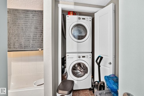 Laundry closet featuring a stacked white washer and dryer unit with a tiled floor - 417 1510 Watt Drive, Edmonton, AB 