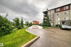 Multi-story residential building with a two-tone exterior, featuring a private balcony, surface parking, and an underground parking entrance - 