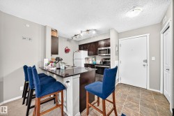 Kitchen featuring dark wood cabinetry, stainless steel appliances, and a breakfast bar with a dark countertop - 