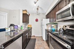Kitchen featuring dark wood-finish cabinetry, stainless steel appliances, and a double basin sink - 