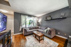 Living area featuring wood-finish flooring, a large window with natural light, and a built-in wall shelf - 