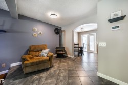Living area featuring a freestanding wood-burning stove, vaulted ceiling, and dark tile flooring - 