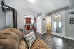 Open concept living space featuring dark tile flooring and a black wood stove - 