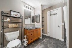 Bathroom featuring a wood vanity with a dark countertop and undermount sink, a tiled backsplash, and dark slate-style flooring - 