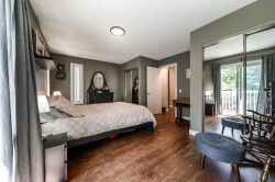 Bedroom featuring wood-finish flooring, mirrored closet doors, a sliding glass door to a balcony, a vertical window, and a ceiling light fixture - 