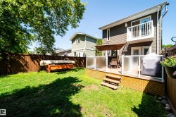 Expansive backyard featuring a wood deck with glass panel railing, a second-story balcony, and a full privacy fence - 