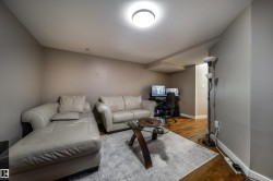 Recessed ceiling lighting illuminates a room featuring wood-finish flooring and neutral wall tones - 