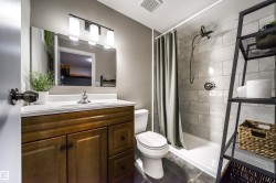 Bathroom featuring a wood-finish vanity with a white countertop, large wall mirror, and a three-light fixture - 