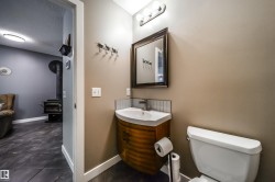 Compact powder room featuring a curved wood-finish vanity with an integrated white sink, brushed nickel faucet, and a subway tile backsplash - 