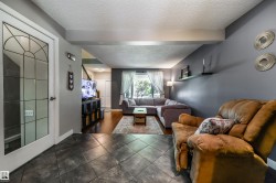 Entryway with patterned glass door, leading to an open living area featuring dark tile flooring - 