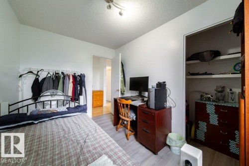 Bedroom featuring wood-finish flooring, white walls, and a built-in closet with shelving - 4224 89 Street, Edmonton, AB 