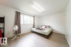Bright room featuring a wide window with dark drapes, light wood-finish flooring, and white walls - 