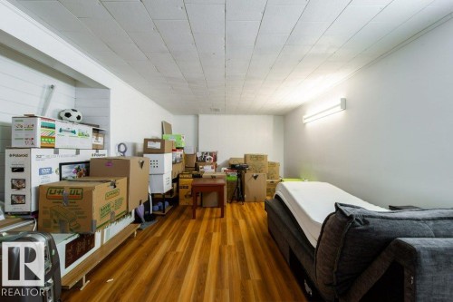 Spacious room featuring wood-finish flooring, white walls, and a dropped panel ceiling - 4224 89 Street, Edmonton, AB 