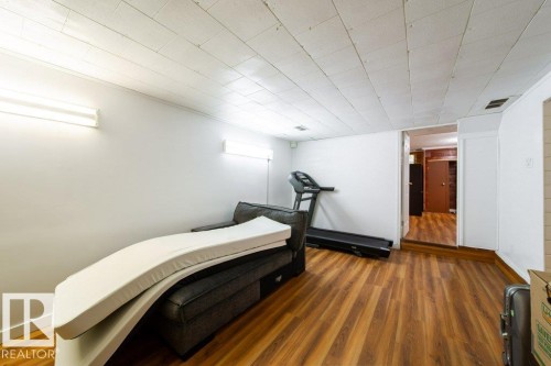 Finished interior space featuring wood-finish flooring, white walls, and a white tile ceiling - 4224 89 Street, Edmonton, AB 