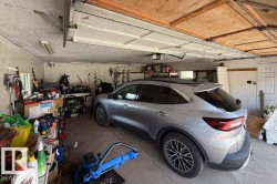 Attached garage with a concrete floor, exposed ceiling joists, and a white interior door - 