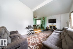 Living room with wood-finish flooring and a white painted brick fireplace - 