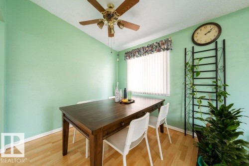 Dining area with wood-finish flooring, a ceiling fan with integrated lighting, and a window featuring vertical blinds and a fabric valance - 4224 89 Street, Edmonton, AB 