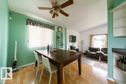 Open-concept living area featuring light wood-finish flooring, a white brick accent wall, and a ceiling fan with light fixture - 