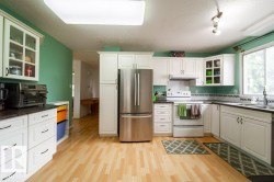 Kitchen featuring light wood-finish flooring, white cabinetry with dark hardware, and a stainless steel refrigerator - 