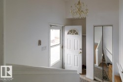 Foyer featuring a decorative chandelier and a solid wood front door with an arched transom window - 