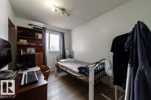 Room featuring wood-finish flooring, a window with dark curtains, and a built-in wooden shelving unit - 4224 89 Street, Edmonton, AB 