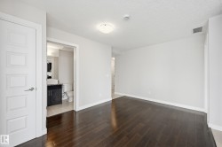 Spacious room with dark wood-finish flooring, white baseboards, and light neutral wall paint - 