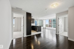 Open concept living area with dark wood-finish flooring extending into the kitchen space - 