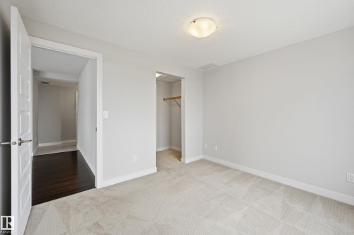 Neutral-toned room featuring light gray walls, textured carpeting, and white baseboards - 528 5151 Windermere Boulevard, Edmonton, AB 
