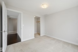 Neutral-toned room featuring light gray walls, textured carpeting, and white baseboards - 