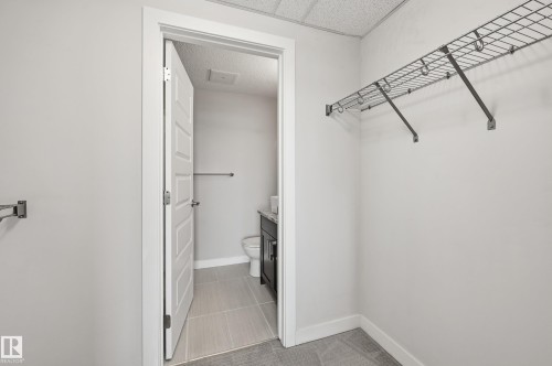 Walk-in closet featuring wire shelving and light gray carpeting - 528 5151 Windermere Boulevard, Edmonton, AB 