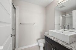 Bathroom featuring a dark wood-finish vanity with a stone countertop, a white rectangular vessel sink, and a chrome faucet - 