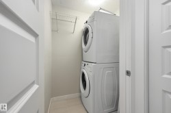 Laundry area featuring a stacked washer and dryer, tile flooring, and a wire shelving unit - 