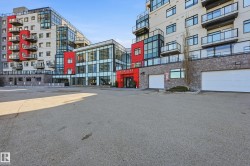 Contemporary multi-story building featuring extensive glazing, red panel accents, and stone-look cladding - 